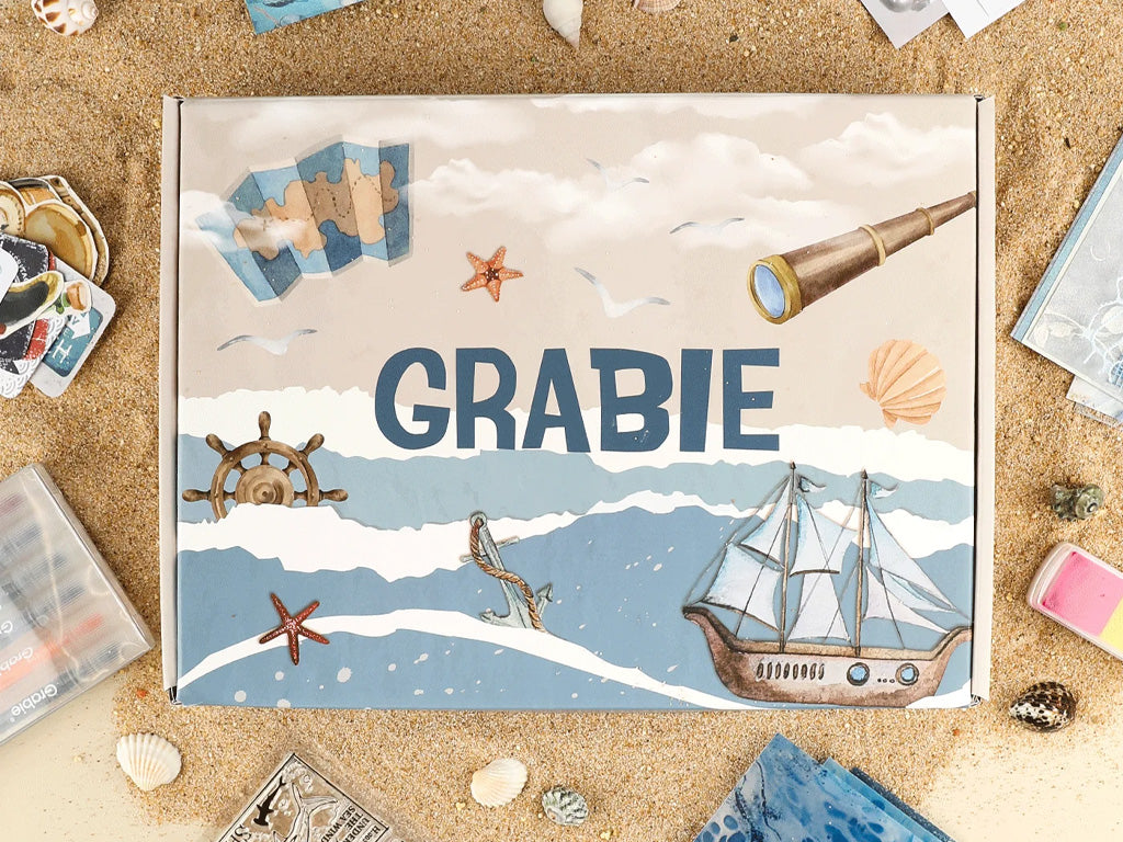 Creative arts and crafts box with nautical illustrations, seashells, and drawing supplies on sand