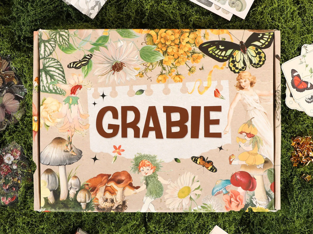 Decorative notebook cover with floral, mushroom, butterfly, and fairy illustrations on grass