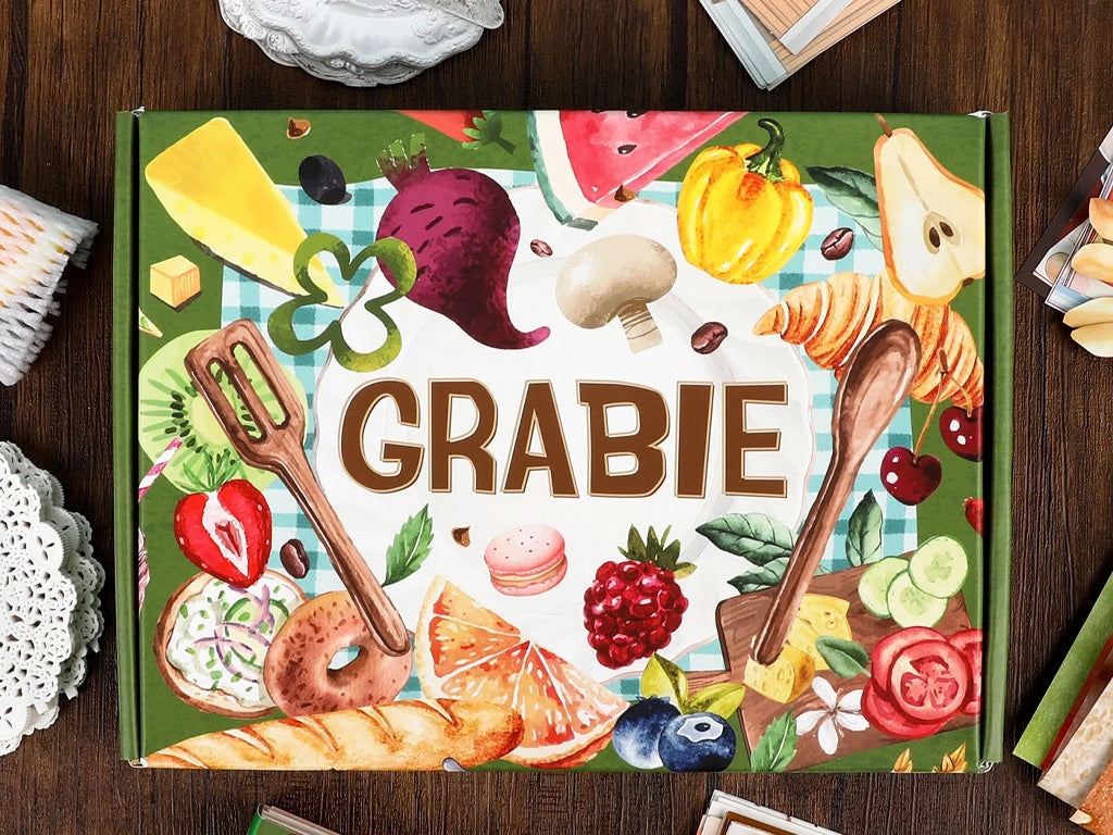 Colorful arts and crafts box with illustrated food items, paintbrushes, and art tools on a table