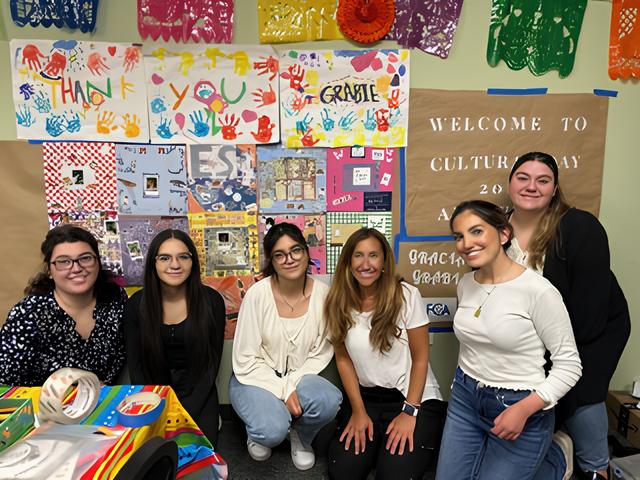 Group of young women at arts and crafts event, colorful handprint thank you poster, Culture Day decorations