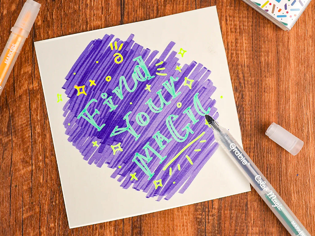 Hand-lettered 'Find Your Magic' art card with colored markers on wood table