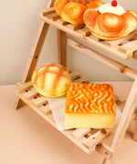 Feel-Good Stress Relief Foam Squishy - Tiger Skin Cake on wooden rack among other squishy desserts in soft warm light