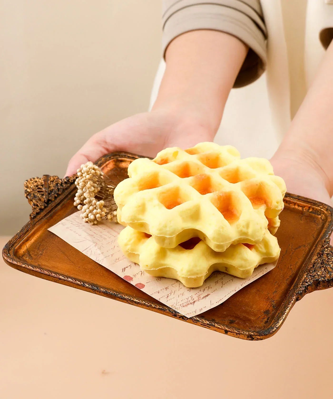 Hands holding a vintage tray with two yellow foam waffles, featuring the Feel-Good Stress Relief Foam Squishy - Waffle Sandwich