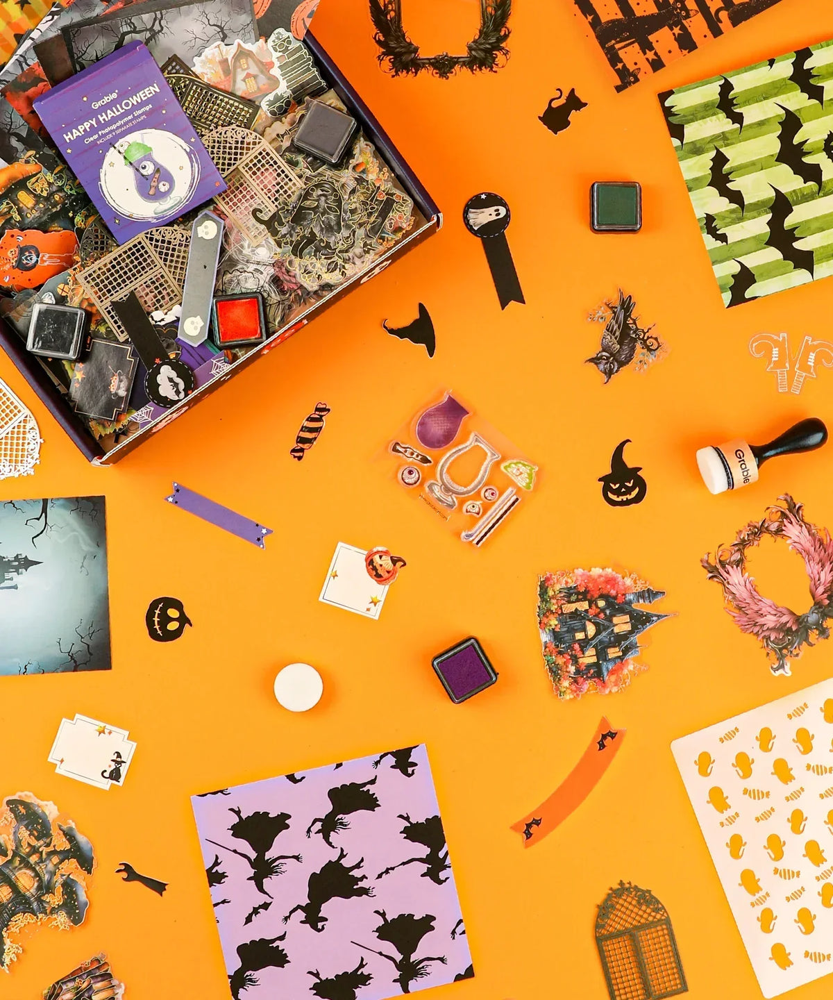 Halloween-Themed Grabie Scrapbook Club Box with stamps, ink pads, themed stickers, and decorative paper for crafting and scrapbooking.