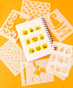 Halloween-Themed Grabie Scrapbook Club Box with pumpkin stencils and Halloween art supplies on orange background