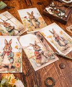 Grabie Exclusive 6 Pack Postcards With 6 Matching Envelopes featuring watercolor rabbits in vintage-style outfits on wooden table