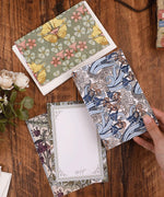 6 Pack Postcards With 6 Matching Envelopes featuring floral and abstract designs on a wooden table with flowers nearby