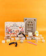 Grabie Bead Box with assorted beads, pliers, tweezers, and bead organizer tray on orange background