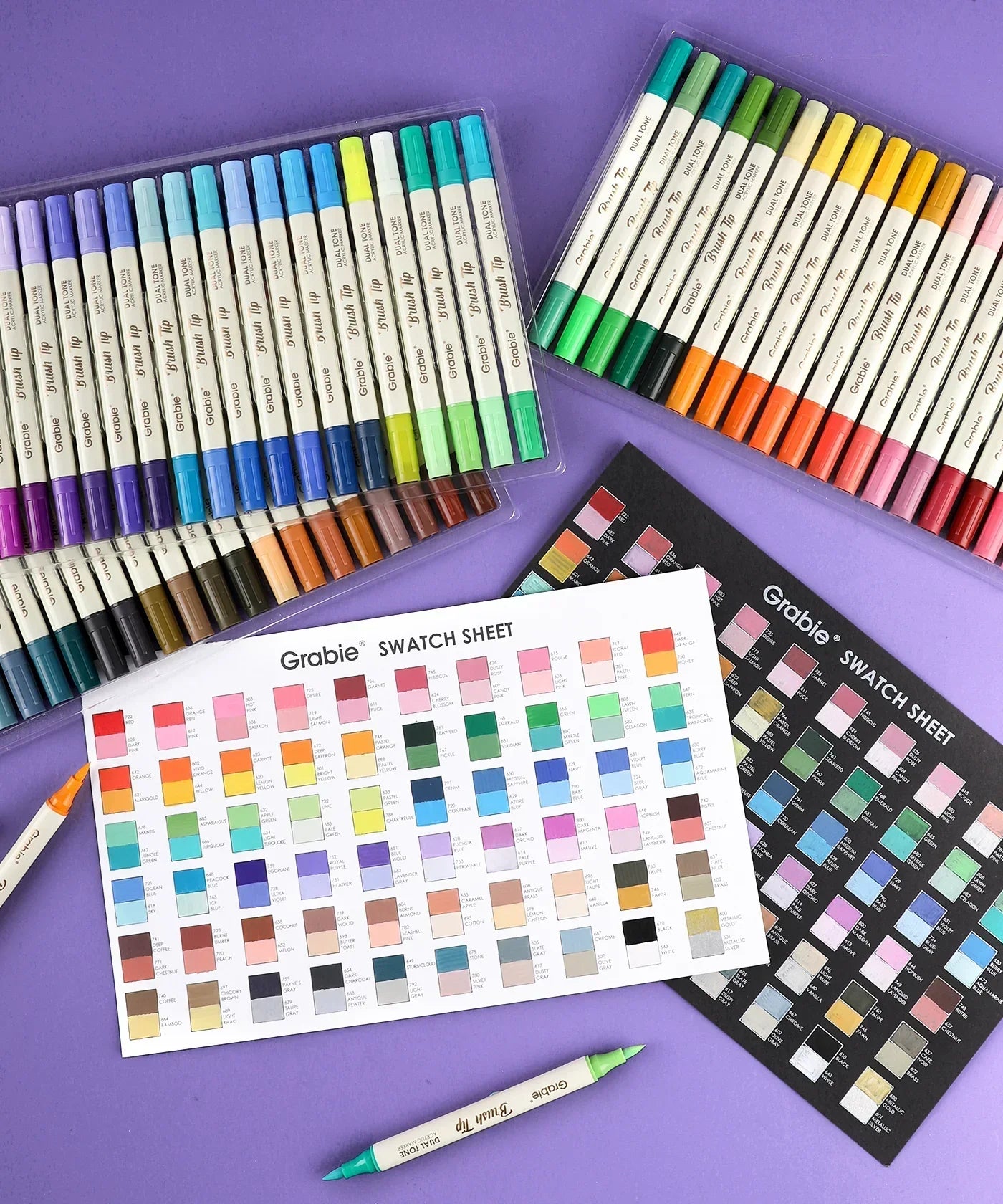 Dual Tone Brush Tip Acrylic Paint Marker Set of 60 with color swatch sheets and markers arranged on purple background