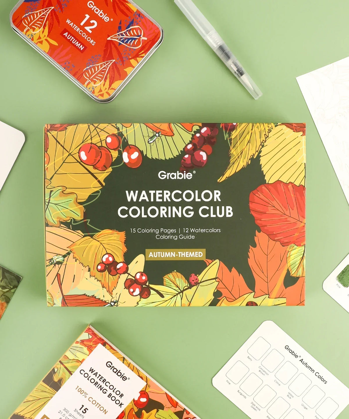 Autumn-Themed Watercolor Coloring Club Box with vibrant fall leaves, berries, and art supplies on green background