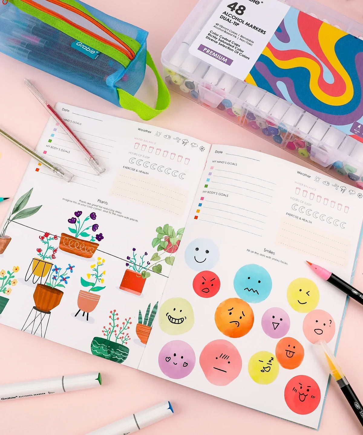 Open "Be You And Love You 28-day Workbook" showing colorful plants and emoji faces with markers and art supplies nearby