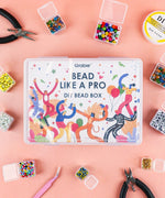 Grabie Bead Box with colorful beads and jewelry-making tools arranged on a peach background
