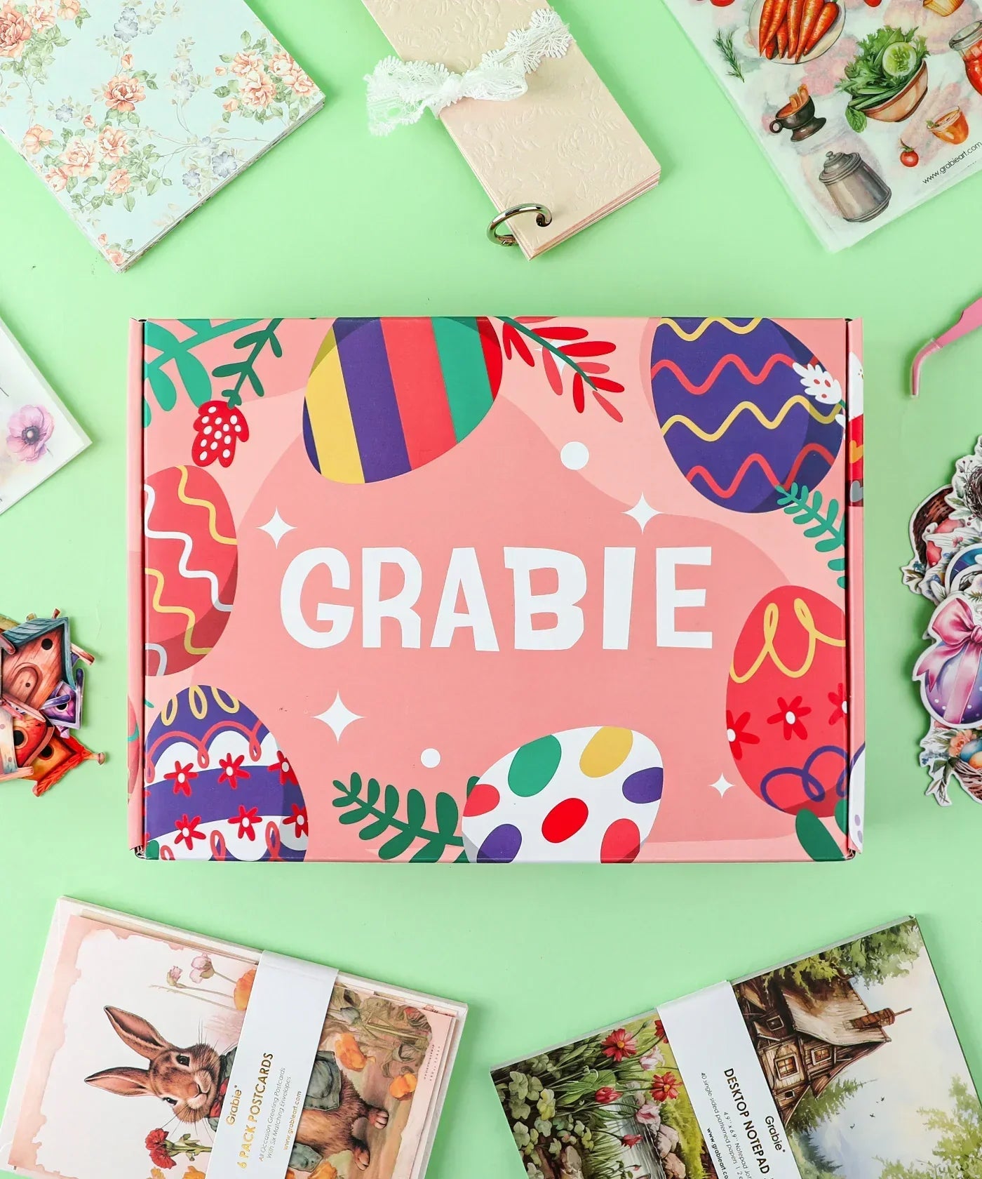 Colorful Easter egg decorated Grabie box surrounded by scrapbook pages and art supplies Easter-Themed Grabie Scrapbook Club Box