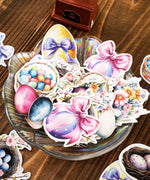 52 Pcs Grabie Exclusive Hoppy Easter Sticker Set featuring colorful Easter eggs and floral designs on a glass dish