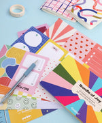 60 Sheets Grabie Exclusive Bundle Of Joy Desktop Notepad Jotter with colorful patterned pages and art supplies on blue background