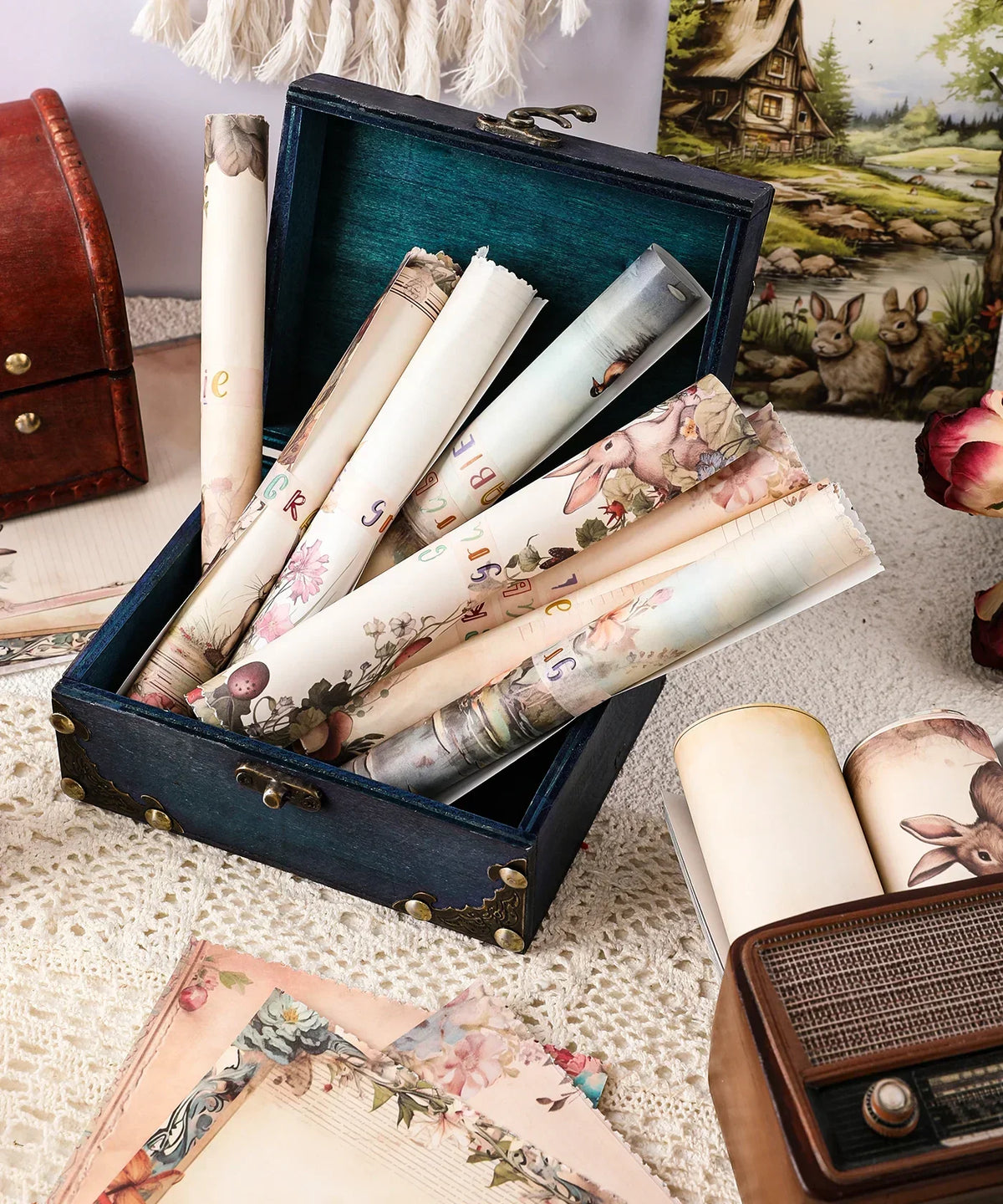 Rolled decorative papers inside a vintage blue box with a floral theme and Grabie Exclusive Desktop Notepad Jotter nearby