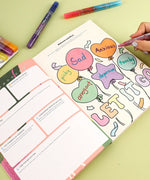 Grabie x AATA Rock Your Inner Strength 4-Week Workbook open with colorful markers and handwritten emotions on balloon illustrations.