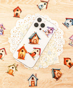 Various colorful birdhouse stickers from the 20 Pcs Grabie Exclusive Fairybird House Sticker Set displayed on a wooden surface and phone.
