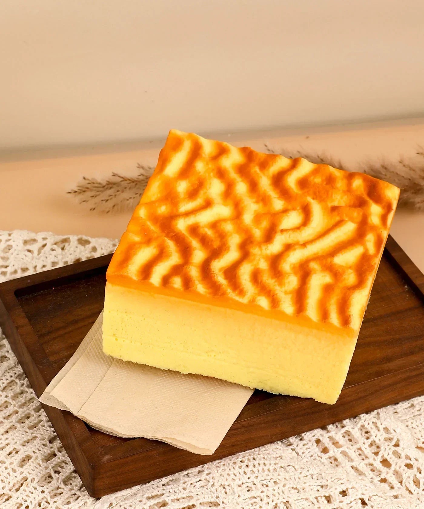 Feel-Good Stress Relief Foam Squishy - Tiger Skin Cake with textured golden top on wooden tray and cloth background