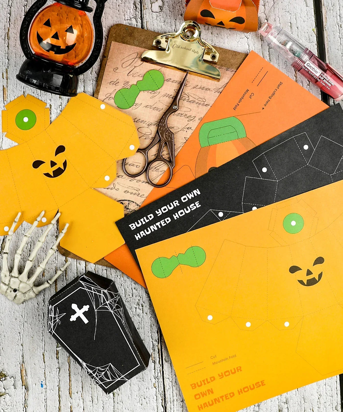 3 Sheets Grabie Exclusive Halloween DIY Kit with pumpkin designs, coffin cutouts, scissors, and crafting tools on wooden surface