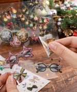 Person peeling a festive beer mug sticker from the 8 Sheets Grabie Exclusive New Year Sticker Set on a wooden table.