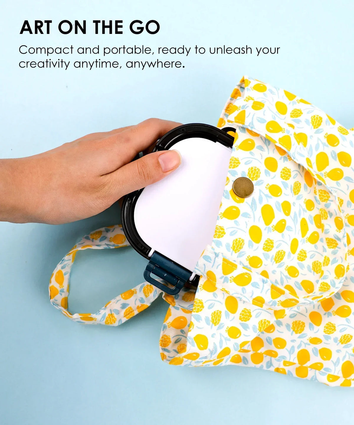 Hand placing 3-in-1 Paint Brush Cleaner Bucket into a yellow patterned portable bag for art on the go