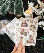 Hand holding 8 Sheets Grabie Exclusive New Year Sticker Set with festive cakes, gifts, and holiday decorations for scrapbooking.