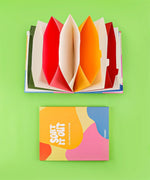 Let Your Feelings Flow Grabie Art Club Box with colorful accordion-style folded art supplies on green background