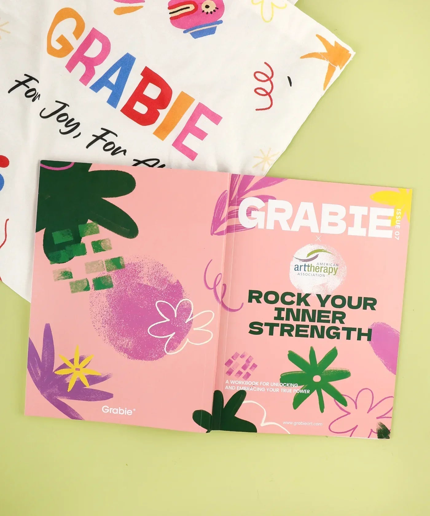 Grabie x AATA Rock Your Inner Strength 4-Week Workbook with colorful floral cover and brand tote bag on green background