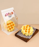 Feel-Good Stress Relief Foam Squishy - Waffle Sandwich displayed in packaging and stacked on a wooden tray.
