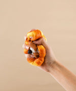 Hand squeezing a realistic foam squishy shaped like a chocolate flower bread, Feel-Good Stress Relief Foam Squishy - Chocolate Flower Bread