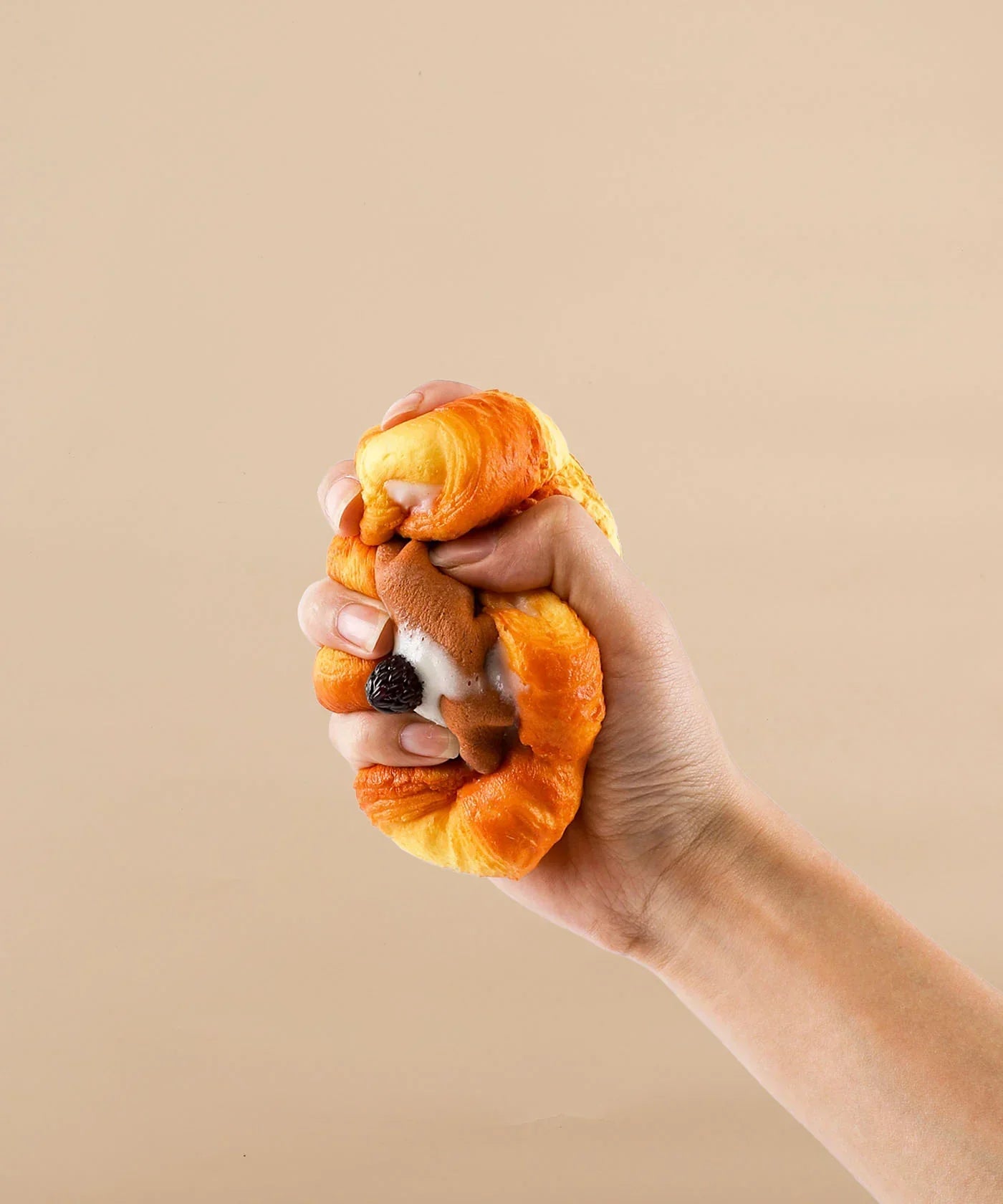 Hand squeezing a realistic foam squishy shaped like a chocolate flower bread, Feel-Good Stress Relief Foam Squishy - Chocolate Flower Bread