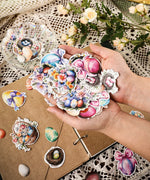 Hands holding colorful Easter egg and flower stickers from the 52 Pcs Grabie Exclusive Hoppy Easter Sticker Set