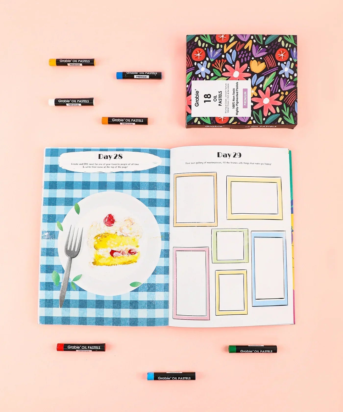 Open art journal with watercolor painting and blank frames, surrounded by colorful oil pastels, Let Your Feelings Flow Grabie Art Club Box