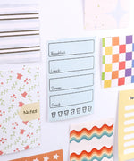 60 Sheets Grabie Exclusive Bundle Of Joy Desktop Notepad Jotter with colorful, patterned notes and reminders on a wall display