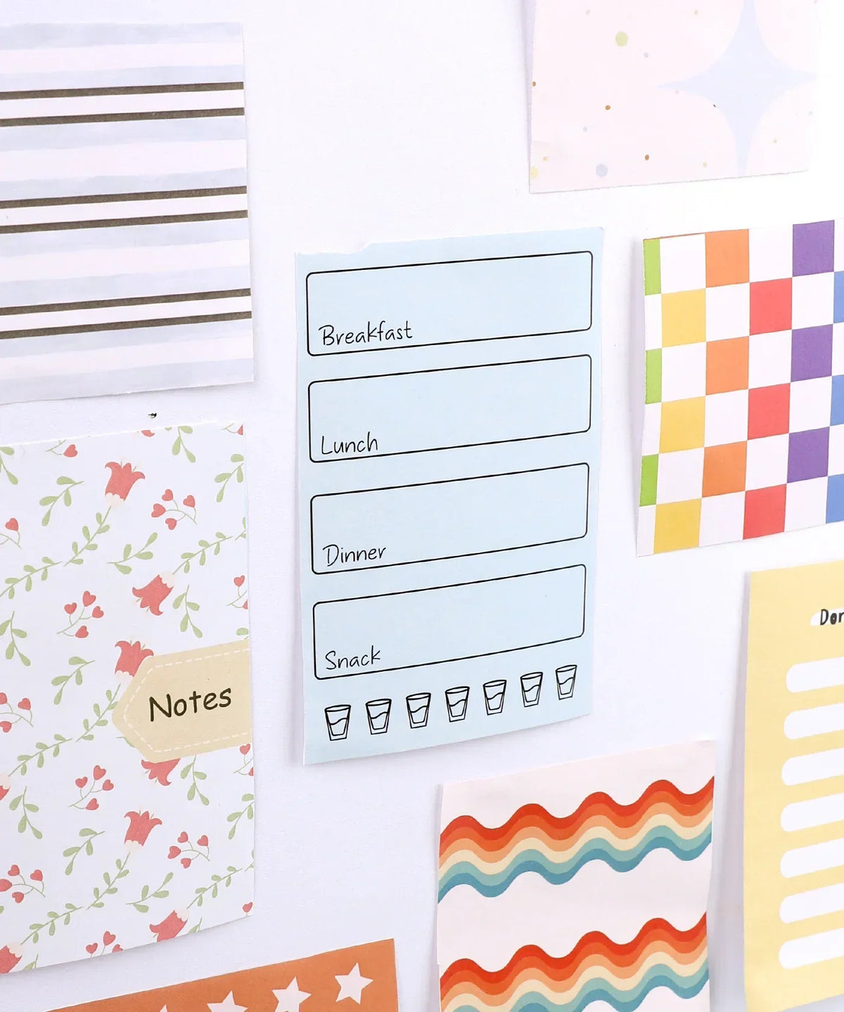 60 Sheets Grabie Exclusive Bundle Of Joy Desktop Notepad Jotter with colorful, patterned notes and reminders on a wall display