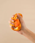 Hand squeezing a Feel-Good Stress Relief Foam Squishy - Fried Egg Bun against a neutral background