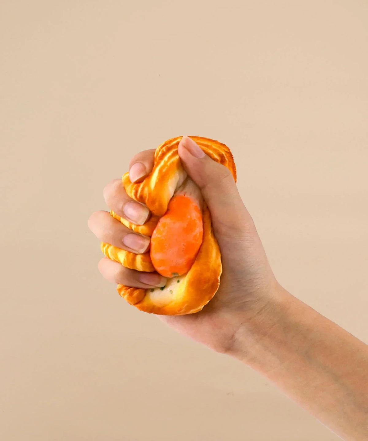 Hand squeezing a Feel-Good Stress Relief Foam Squishy - Fried Egg Bun against a neutral background