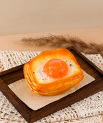 Soft stress relief foam squishy shaped like a fried egg bun with realistic orange yolk and toasted bread edges.