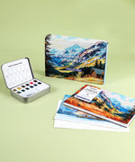 Landscape-Themed Watercolor Coloring Club Box with watercolor palette and landscape-themed coloring books on green background