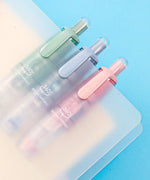 Three pastel-colored Double-Sided Adhesive Dot Runner tools clipped to translucent folders on a blue background
