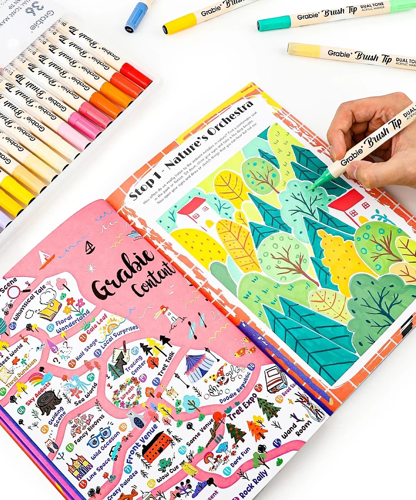 Person coloring a vibrant nature-themed page with markers next to a detailed colorful map in the Unplug And Go Outside 30-day Workbook