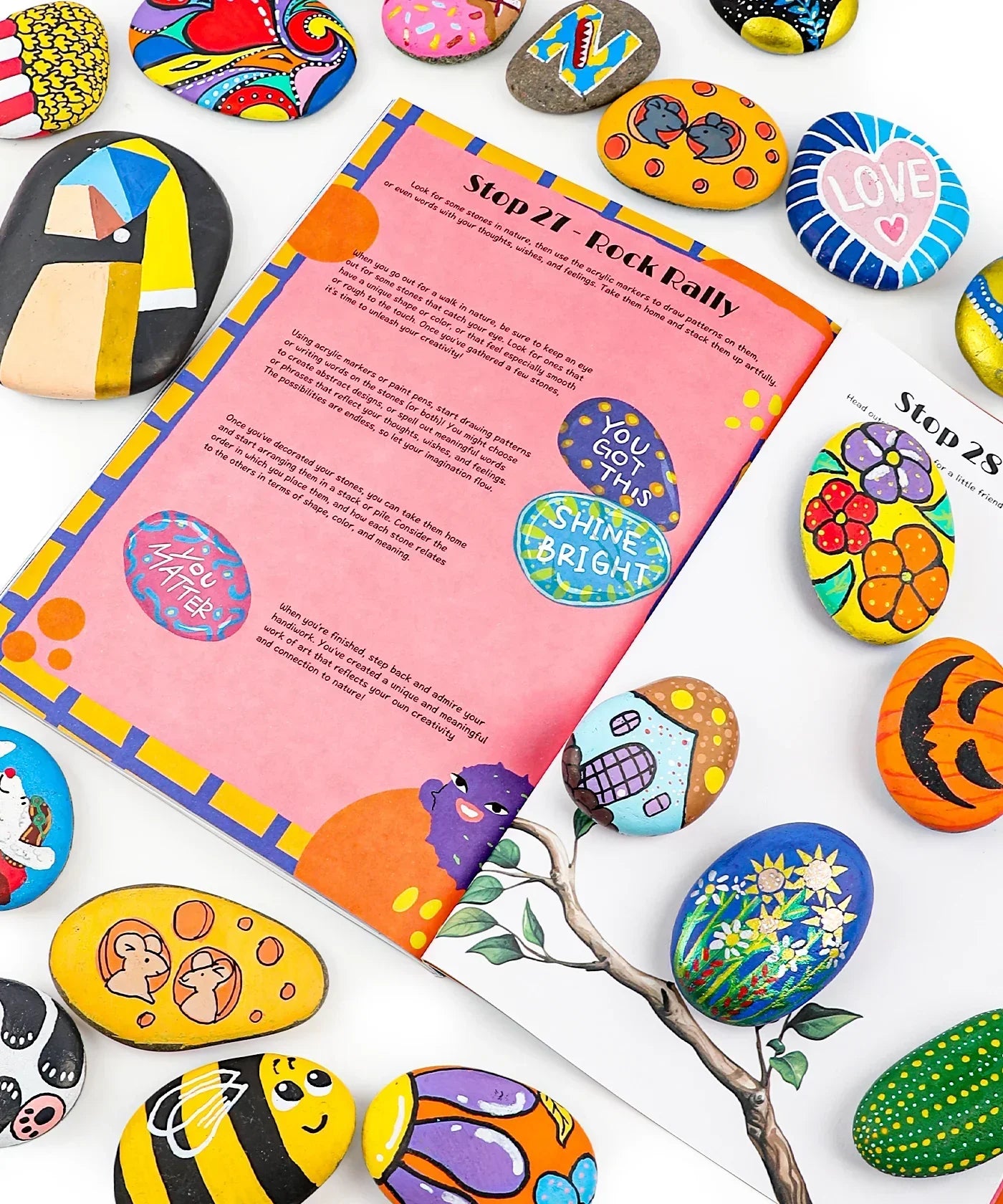 Unplug And Go Outside 30-day Workbook open amid colorful hand-painted stones with positive messages and designs