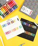 Extra Fine Tip Acrylic Paint Marker Set of 28 with colorful swatch sheets and art supplies on a bright yellow background