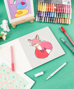 Grabie Acrylic Paint Marker Set displayed with colorful drawings and markers on a green workspace background