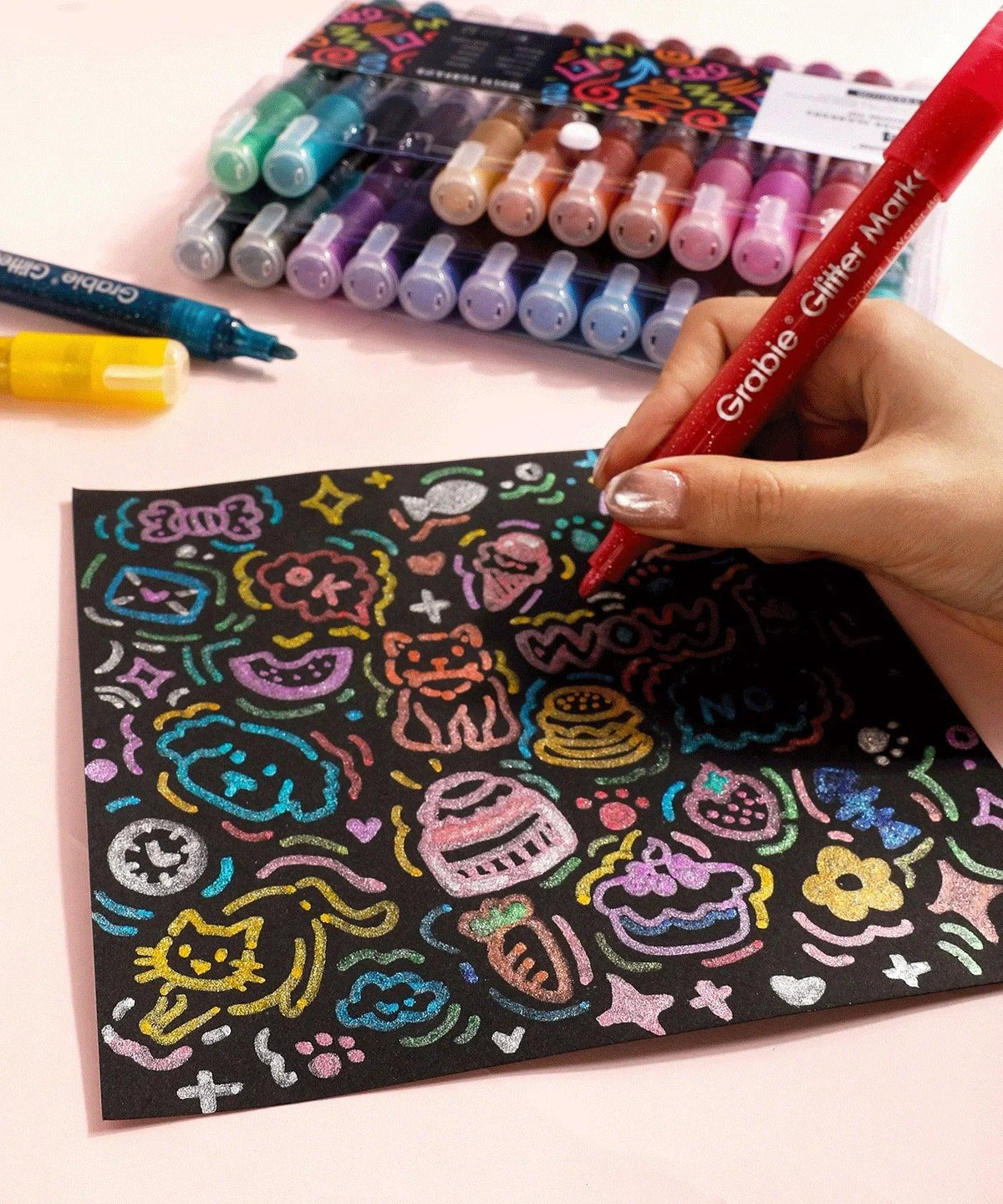 Iridescent Glitter Acrylic Paint Marker Set used for colorful drawings on black paper with glittery effects and vibrant colors.
