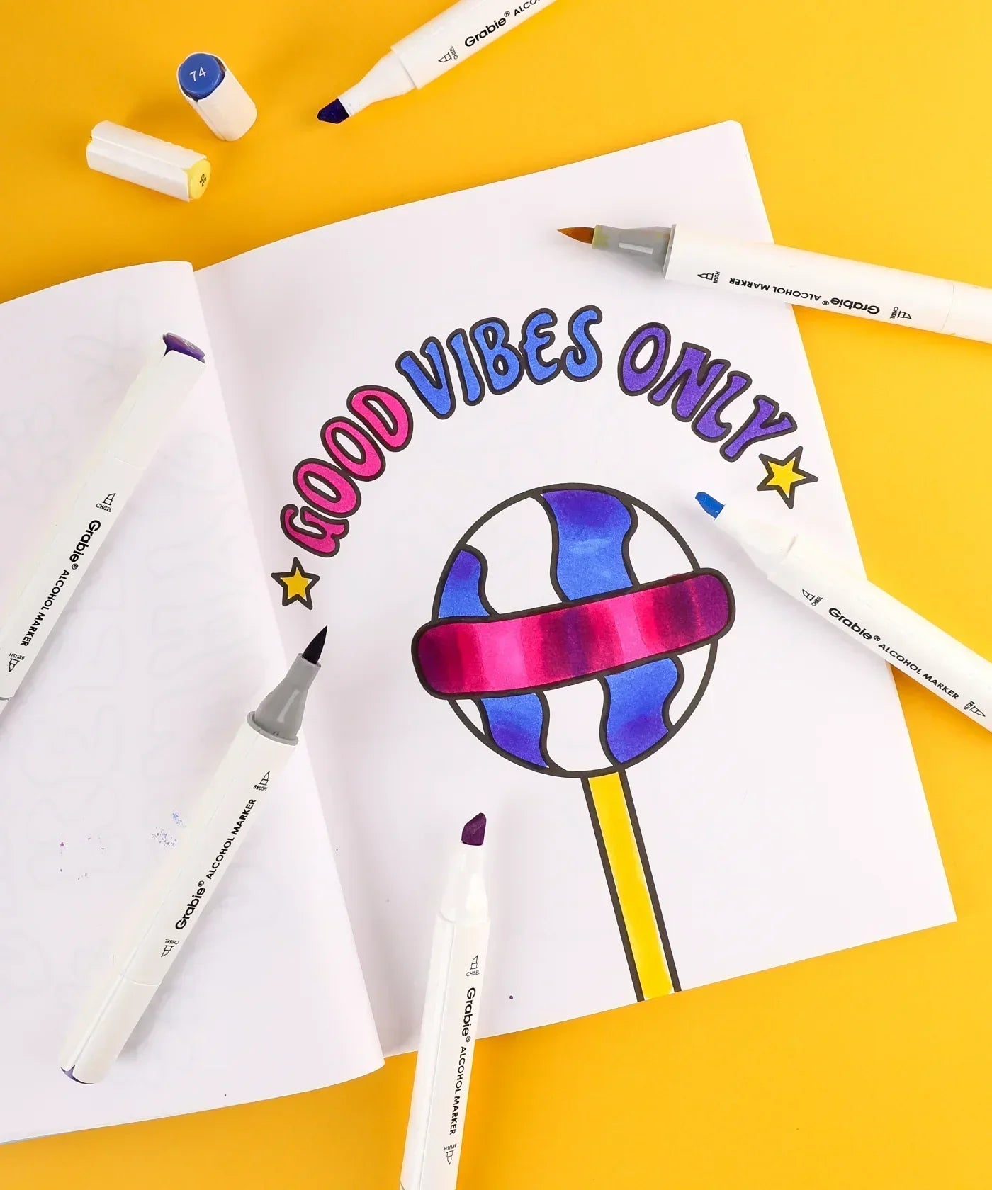 Open coloring book with a colorful "Good Vibes Only" design and Dual Tone Brush Tip Acrylic Paint Marker Set With Coloring Book markers nearby