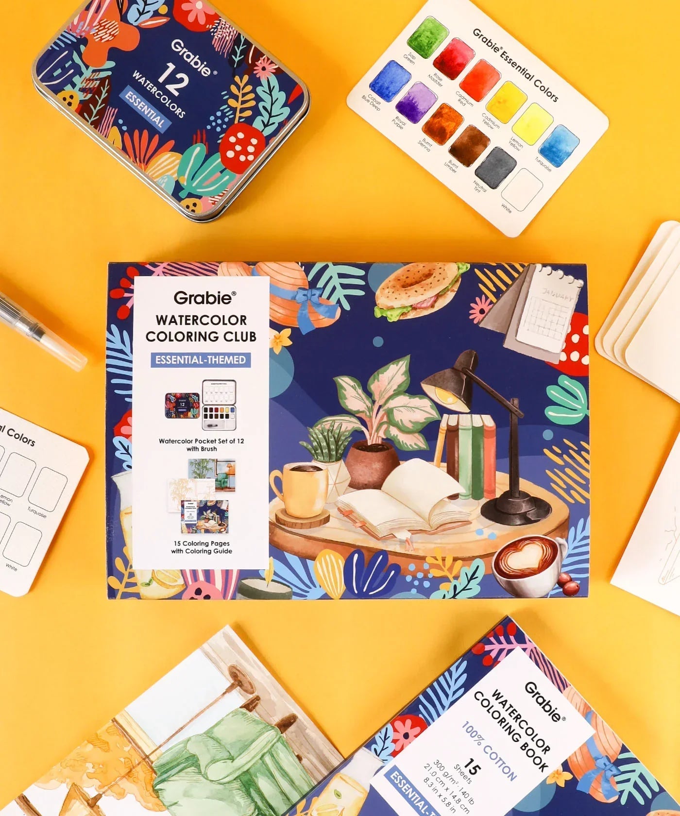 Essential-Themed Watercolor Coloring Club Box with watercolor markers, color swatches, and artistic supplies on yellow background