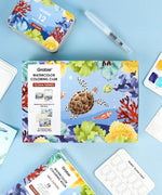 Ocean-Themed Watercolor Coloring Club Box with ocean illustrations, watercolor set, brush pen, and coloring pages laid out on blue background