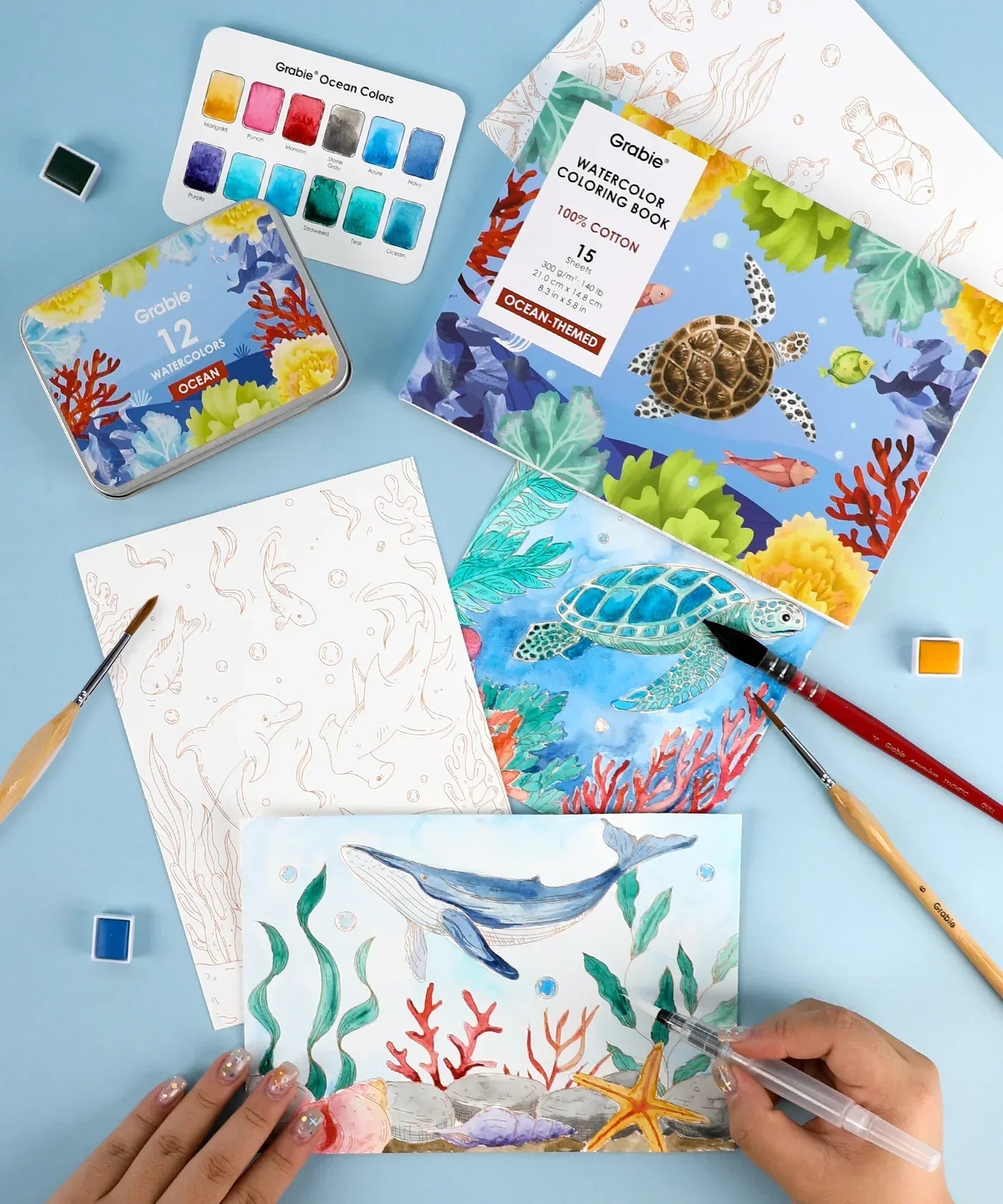 Ocean-Themed Watercolor Coloring Club Box with brushes, watercolor palette, and sea animal illustrations being painted by hand
